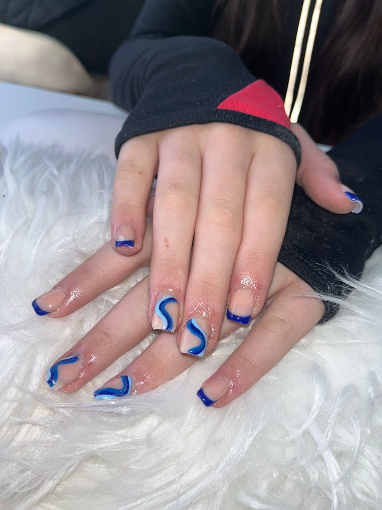 Close-up of trendy blue swirl nail art on natural nails, created at Lorellin Salon.