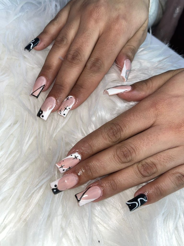 Close-up of black and white nail art with geometric designs, created at Lorellin Salon.